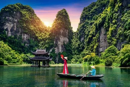 Woman wearing a red dress and a traditional Vietnamese outfit on a small boat, blue water.